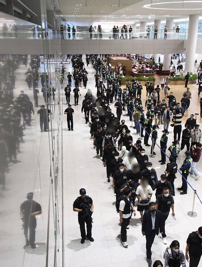 캄보디아 현지 범죄단지 단속으로 구금됐던 한국인 피의자 64명이 지난 18일 인천국제공항 제2터미널을 통해 송환되고 있다. 단일 국가 기준 역대 최대 규모로 이뤄진 이번 송환 작전에는 호송 경찰관만 190여명이 투입됐다. 연합뉴스