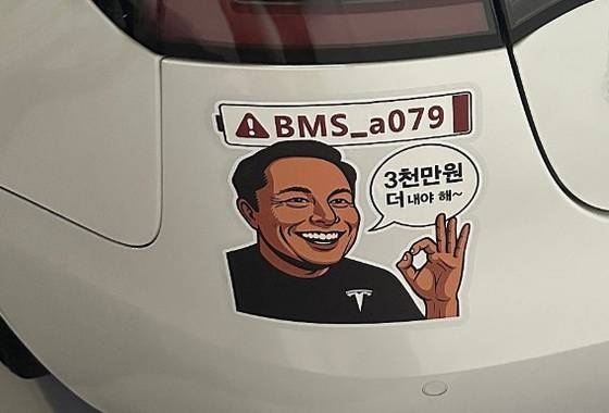 테슬라 차량 이용자 모임 '테슬라코리아클럽' 회원들이 BMS_a079 오류를 지적하기 위해 일론 머스크 테슬라 CEO의 얼굴을 풍자해 만든 스티커. 해당 회원들은 스티커 붙이기 운동을 하고 있다. 테슬라코리아클럽 캡처