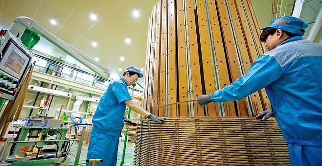 LS일렉트릭 직원들이 초고압직류송전(HVDC) 변압기에 들어가는 권선을 수직 권선기에 감고 있다. 권선은 전류를 흘려 자기장을 만드는 구리선 코일로, 변압기 내부에서 전압을 변환하는 데 필수다. /LS일렉트릭 제공
