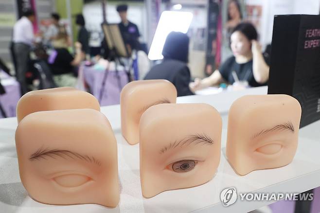 눈썹 반영구 화장 9월 15일 서울 강남구 SETEC에서 열린 'PTS문신 산업 박람회'(뷰티타투페어)에서 참관객들이 눈썹 반영구 화장에 대해 설명을 듣고 있다.[연합뉴스 자료사진]