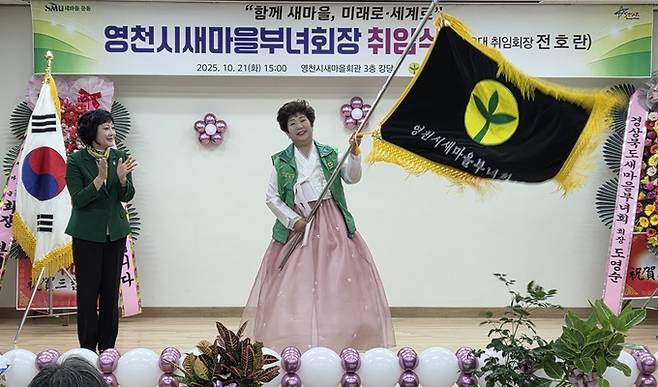 ▲ 21일 전호란 영천시새마을부녀회 신임 회장이 도영순 경북도부녀회장으로부터 새마을기를 전달받고 깃발을 흔들고 있다. 권오석 기자