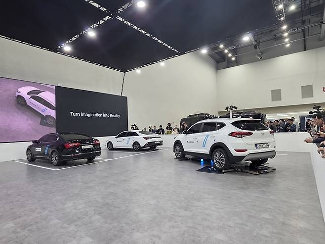 ▲ HL로보틱스가 대구 엑스코에서 열린 FIX 2025 현장에서 자율주행 주차로봇의 주차 과정을 시연하고 있다. 차량을 들어 올린 로봇 2대가 곡선을 그리며 주차 공간으로 이동하고 있다. 전재용 기자