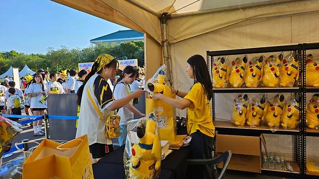 포켓몬 굿즈를 구매하는 참가자들, 여미지식물원 부스에서 인기 있는 피카츄 인형을 받고 있다. (제주관광공사 제공)