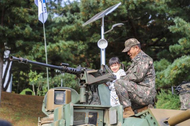 ▲ 육군21사단 군인가족의 날 행사에 참석한 군인 자녀가 K1E1 전차 위에서 장비를 체험하고 있다.