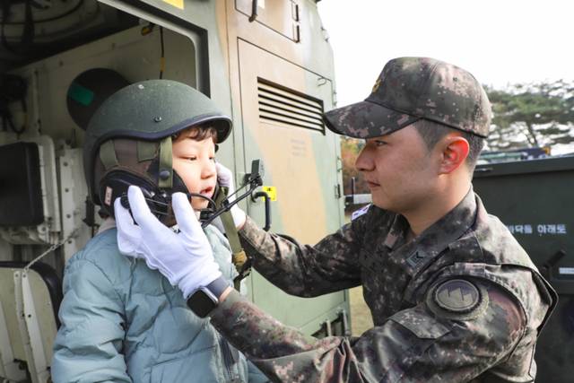 ▲ 육군21사단 군인가족의 날 행사에 참석한 군인 자녀가 차륜형 장갑차에 탑승해 기갑헬멧을 착용하고 있다.