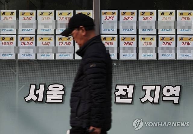한 시민이 부동산 공인중개업소 매물정보 게시판 앞을 지나가고 있다. [연합뉴스]