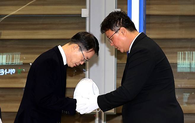 Ahn Jung-man, chief of the Gyeongbuk Provincial Police Agency's criminal investigation unit, left, receives an urn containing the cremated remains of murdered university student Park Min-ho at Incheon International Airport on Oct. 21. [NEWS1]