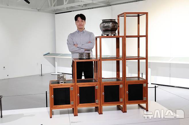 [포항=뉴시스] 박진희 기자 = K-헤리티지 아트전 '이음의 변주‘ 참여작가 조현영(경남 무형문화재 소목장 이수자)이 23일 경북 포항시 문화예술팩토리 아트갤러리에서 전시중이 '책장' 작품 앞에서 포즈를 취하고 있다. 2025.10.23. pak7130@newsis.com