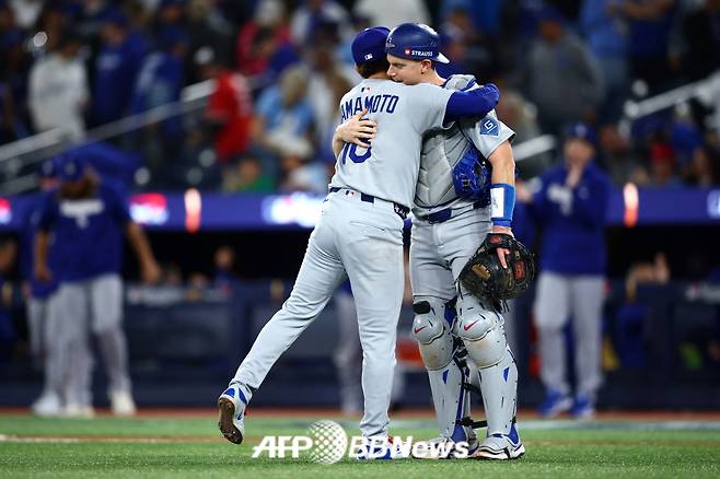 LA 다저스 야마모토 요시노부(왼쪽)가 26일(한국 시각) 캐나다 온타리오주에 위치한 로저스 센터에서 펼쳐진 2025 미국 프로야구 메이저리그(MLB) 포스트시즌 월드시리즈 2차전에서 승리 후 포수 윌 스미스와 기쁨의 포옹을 나누고 있다. /AFPBBNews=뉴스1