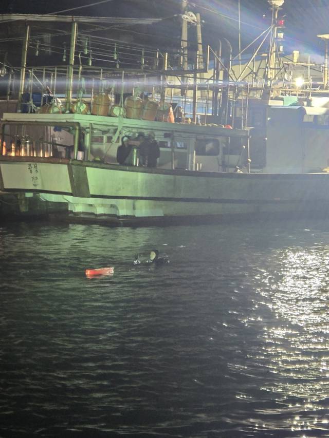 27일 밤 부산 기장군 학리항 차량 추락 사고 현장에서 울산해양경찰서 경찰관들이 침수 차량의 탑승자를 구조하기 위해 수색 작업을 벌이고 있다. 울산해경 제공