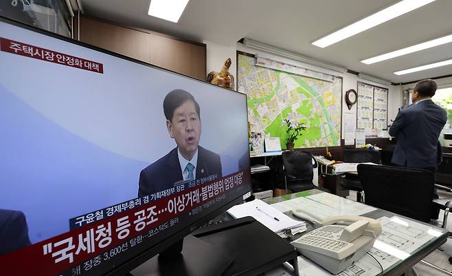 A television at a real estate agency in Seoul airs news coverage of the government’s new housing market stabilization measures on October 15. All 25 districts of Seoul and 12 areas in Gyeonggi Province have been newly designated as regulated zones, including adjusted areas and speculative overheating districts. [YONHAP]