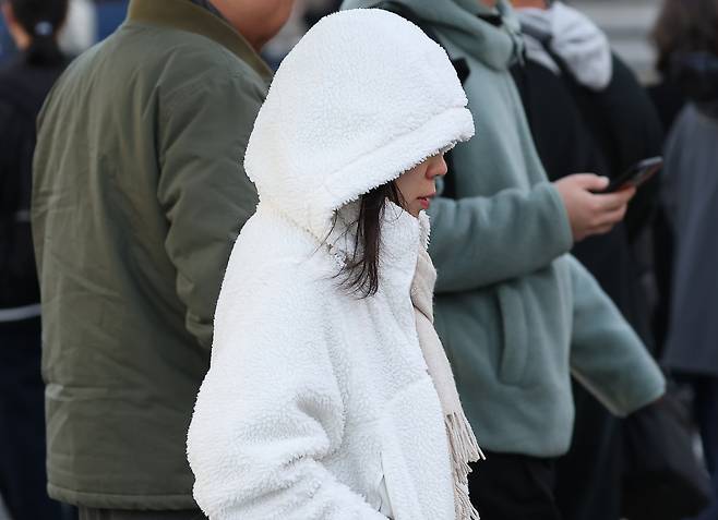 Commuters cross a street near Gwanghwamun Square in central Seoul on Oct. 28, as morning temperatures dropped further than the previous day, bringing an early taste of winter. [YONHAP]