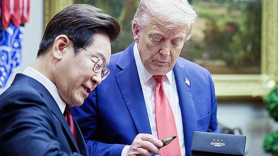 President Lee Jae Myung, left, presents U.S. President Donald Trump with a fountain pen he used to sign the guestbook during the Korea-U.S. summit held at the White House in Washington on Aug. 25. [JOINT PRESS CORPS]