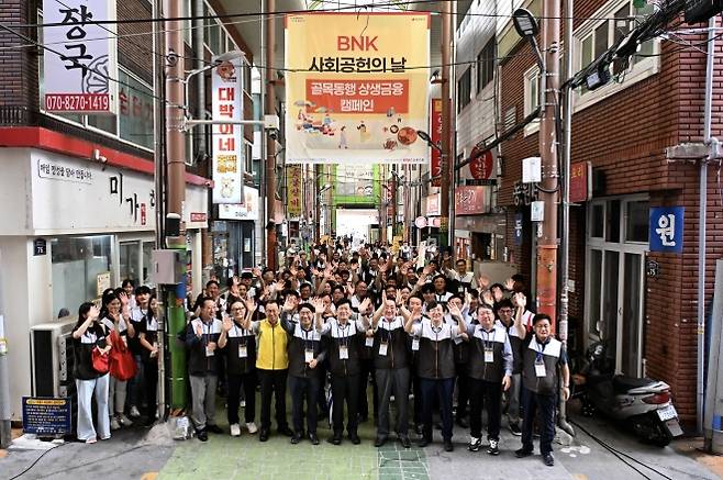 추석을 앞둔 지난달 BNK부산은행 임직원들이 지역 복지관에 전달할 물품을 전통시장에서 구매하는 ‘골목동행 상생금융’ 캠페인을 하고 있다.  BNK부산은행 제공