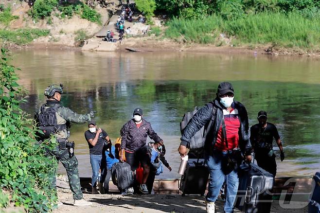 24일(현지시간) 미얀마 KK 파크 단지에서 일하던 근로자들이 짐을 들고 모에이 강을 건너 태국으로 피신하고 있다. 2025.10.24. ⓒ AFP=뉴스1 ⓒ News1 이정환 기자