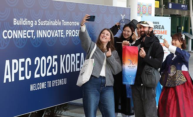 Ahead of APEC 2025, foreign tourists pose for a photo with staff members at a welcome booth set up by the Ministry of Culture, Sports and Tourism at Gyeongju Station, on Sunday. (Yonhap)