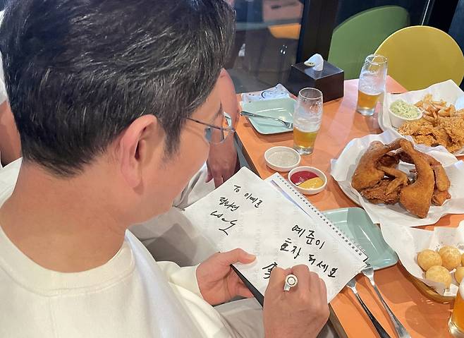 Samsung Electronics Chair Lee Jae-yong signs an autograph for a child during a gathering with Nvidia CEO Jensen Huang and Hyundai Motor Group Executive Chair Chung Euisun at a chicken restaurant in Samseong-dong, Seoul, Thursday. (Yonhap)