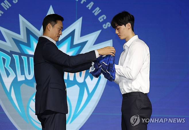 삼성화재 유니폼 입는 이우진 (서울=연합뉴스) 김성민 기자 = 27일 서울 강서구 메이필드 호텔에서 열린 '2025-2026 한국배구연맹(KOVO) 남자 신인선수 드래프트'에서 김상우 삼성화재 감독이 1라운드 2순위로 지명한 이우진(오른쪽)에게 유니폼을 입혀주고 있다. 2025.10.27 ksm7976@yna.co.kr