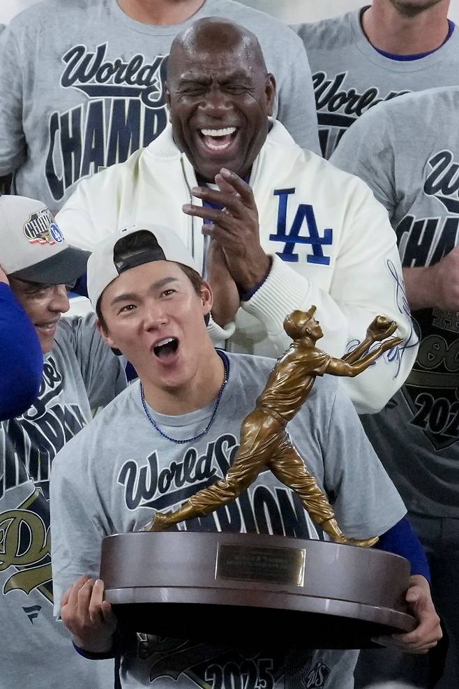 Los Angeles Dodgers World Series MVP Yoshinobu Yamamoto holds his trophy as owner Magic Johnson celebrates their win in Game 7 of baseball's World Series against the Toronto Blue Jays, Sunday, Nov. 2, 2025, in Toronto. AP연합뉴스