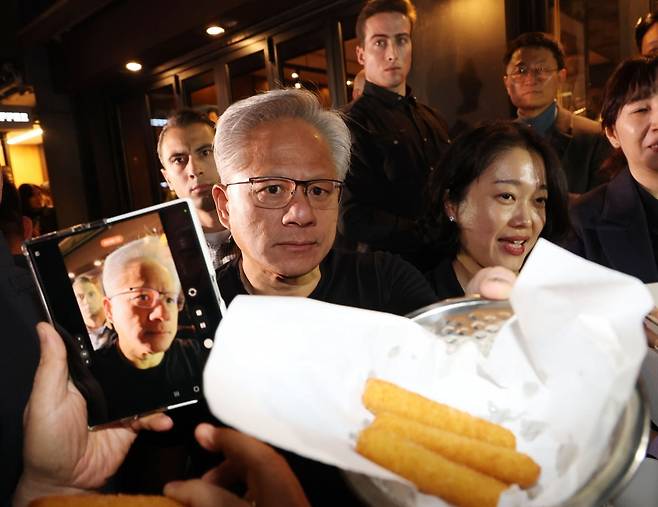 젠슨황 엔비디아 최고경영자가 30일 이재용 삼성전자 회장, 정의선 현대자동차그룹 회장과 서울 강남구 깐부치킨에서 치킨 회동 중 치즈스틱을 시민들에게 내밀고 있다. 사진=한국경제신문