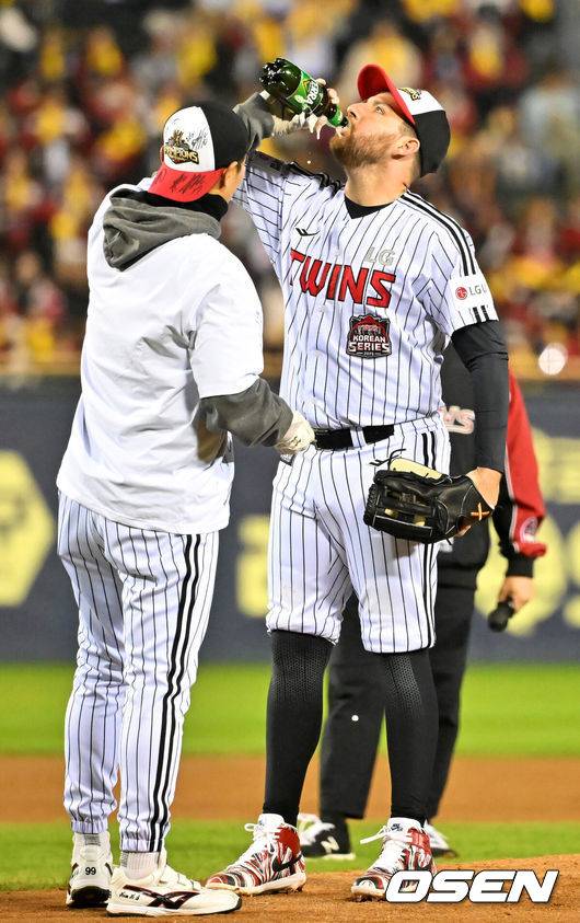 [OSEN=잠실, 민경훈 기자] 2025 시즌 통합 우승을 거머쥔 LG 트윈스가 1일 오후 서울 잠실야구장에서 ‘한국시리즈 통합우승 IN 잠실' 행사를 가졌다.이날 행사에는 팬들을 위한 트로피 퍼포먼스, 선수단 그라운드 행진, 비하인드 스몰토크, 선수단 샴페인 샤워, 이벤트 매치 등 다양한 프로그램이 펼쳐졌다.팬들을 위한 이벤트 경기에서 투수로 나선 LG 오스틴이 마운드 위에서 김광삼 투수코치에게 맥주를 받아 마시고 있다. 2025.11.01 / rumi@osen.co.kr