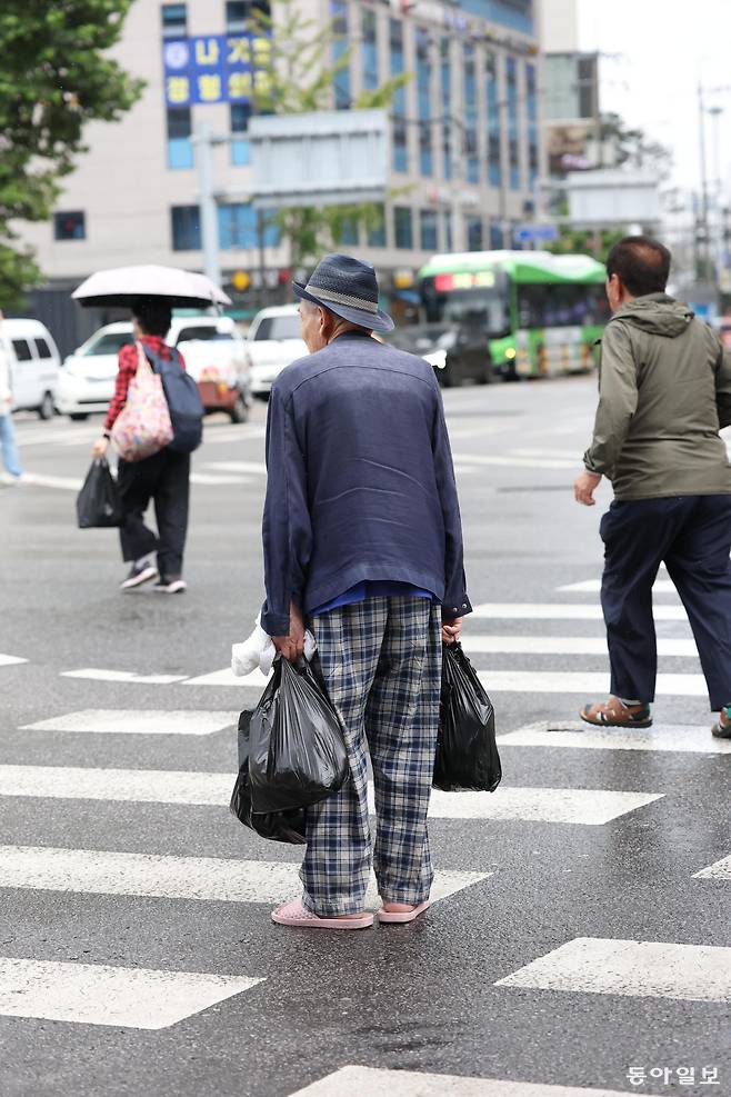 서울의 한 차도에서 어르신이 횡단보도 중간에 서 신호대기 중인 차들을 바라보고 있다. 동아일보DB