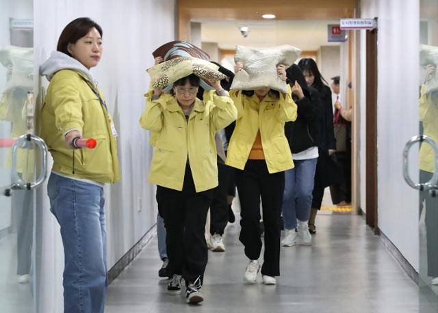 지난달 대구 달서구청에서 진행된 지진 대피 훈련에서 구청 직원들이 안내 방송에 따라 방석으로 머리를 보호하며 대피소로 이동하고 있다. 대구=뉴스1
