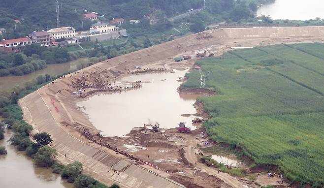 북한의 건설노동자들이 압록강 하류에서 지난해 대홍수로 유실된 제방을 쌓고 있다. <박진관기자>
