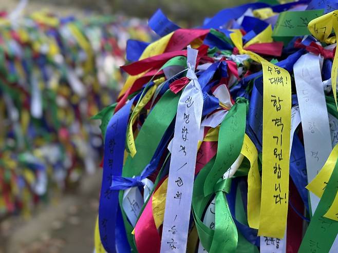 Ribbons bearing the wishes of parents who visited Chiljangsa decorate a bridge on the temple premises. The yellow ribbon reads: "Suneung jackpot! Praying for success on the exam!" (Lee Seung-ku/The Korea Herald)