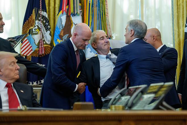 6일(현지 시각) 워싱턴DC 백악관 집무실에서 비만치료제 가격 인하 관련 발표를 하던 중 도널드 트럼프 미국 대통령 뒤에 서 있던 한 제약사 임원이 쓰러지려 하자 주변 사람들이 그를 부축하고 있다. /EPA 연합뉴스