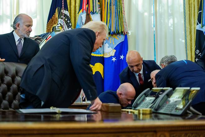 6일(현지 시각) 워싱턴DC 백악관 집무실에서 도널드 트럼프 대통령이 쓰러진 제약사 임원을 확인하고 있다./EPA 연합뉴스