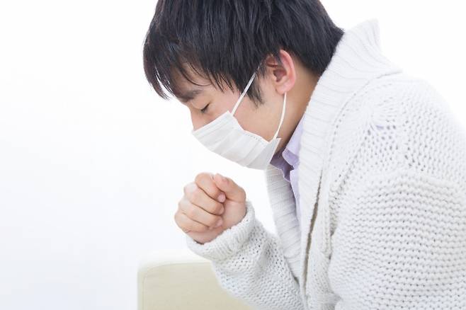 마스크를 착용한 채 기침하는 남성. 123rf