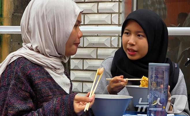 8일 경북 구미에서 열리고 있는 '2025 구미라면축제' 행사장을 찾은 외국인 방문객이 주문한 라면을 먹으며 즐거운 시간을 보내고 있다. 라면축제는 오는 9일까지 구미역 일대에서 계속된다. 2025.11.8/뉴스1 ⓒ News1 정우용 기자