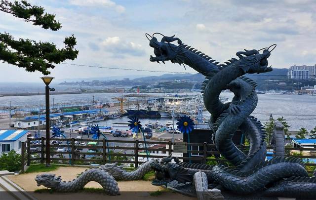 구룡포 공원의 아홉마리 용이 승천하는 모습의 조형물.조형물 뒷편으로 구룡포 항구가 보인다.