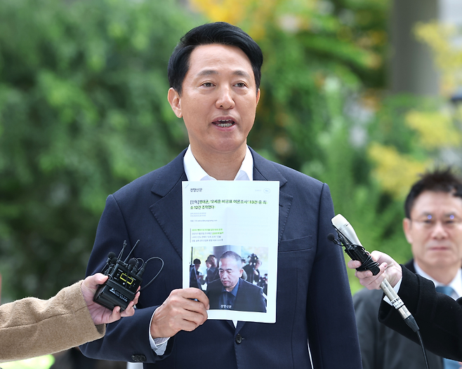 오세훈 서울시장이 8일 ‘여론조사비 대납 의혹’을 수사하는 민중기 특별검사팀의 사무실이 마련된 서울 KT광화문빌딩 웨스트에 조사를 받기 위해 출석하며 경향신문 기사를 들어보이고 있다. 연합뉴스