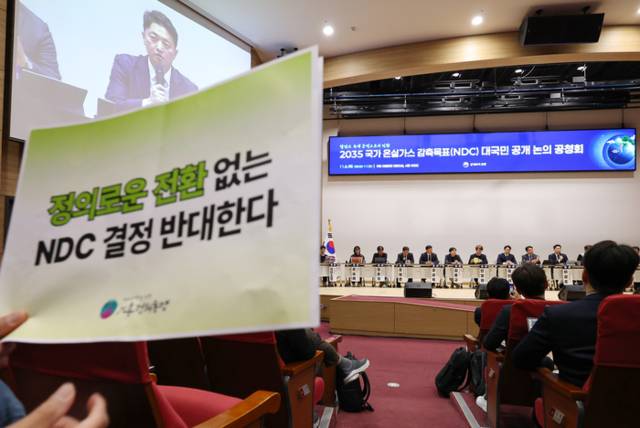 ▲ 6일 서울 여의도 국회 의원회관에서 열린 2035 국가 온실가스 감축 목표(2035 NDC) 대국민 공개 논의 공청회에서 안영환 탄소중립녹색성장위원회 기후변화정책 분과위원장이 좌장으로 토론을 진행하는 가운데 한 참석자가 2035 NDC 정부안에 반대한다는 내용을 담은 손팻말을 들고 있다. 연합뉴스
