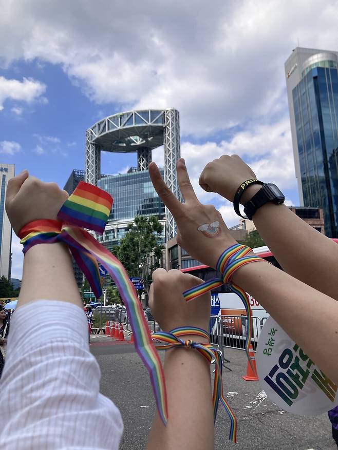 2025년 6월 서울퀴어문화축제에 참석한 유정과 애인이 무지개색 리본을 매고 ‘브이’(V)를 그리고 있다. 유정 제공