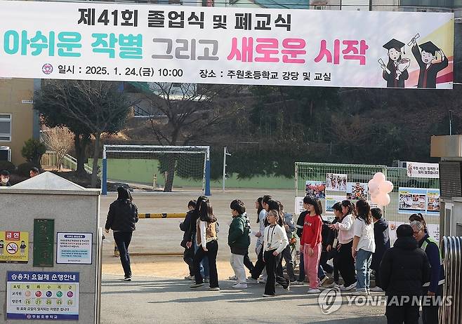 "폐교, 아쉬운 작별 그리고 새로운 시작" 졸업식을 끝으로 폐교에 들어가는 한 초등학교 졸업식이 2025년 1월 열렸다. 졸업식을 마친 학생들이 선생님과 함께 교정 곳곳을 핸드폰 사진에 담으며 추억을 남기고 있다. 
[연합뉴스 사진]
