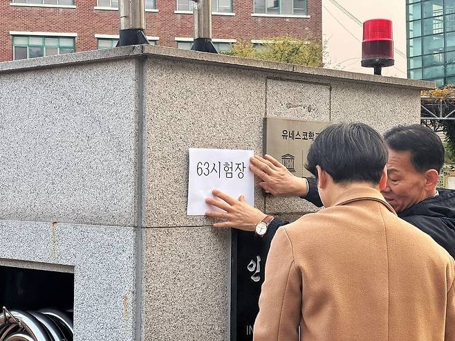 ▲ 13일 오전 2026학년도 대학수학능력시험이 실시되는 인천 남동구 인천남고등학교 현수막에 시험자이 잘못 기재돼 관계자들이 시험장 명을 정정하고 있다. /홍준기 기자 hong@incheonilbo.com