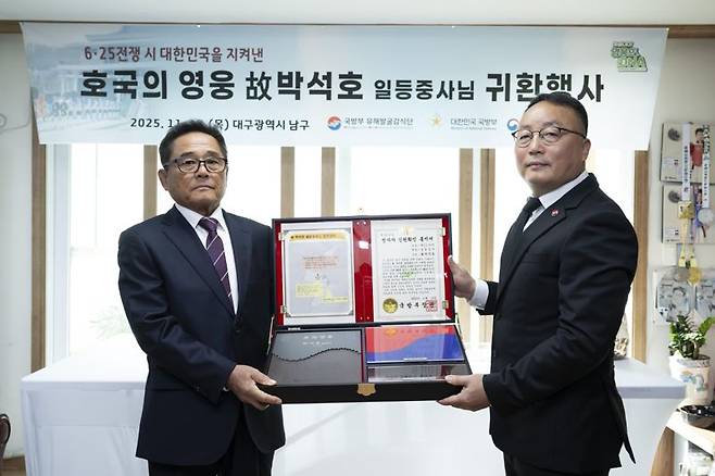 국방부유해발굴감식단장 직무대리 조해학 중령(육군 ·오른쪽)이 고 박석호 일등중사의 유가족 대표인 친조카 박용철 씨(73세·왼쪽)에게 고인의 인식표 등이 담긴 호국의 얼 함을 전달하고 있다. 국방부 제공