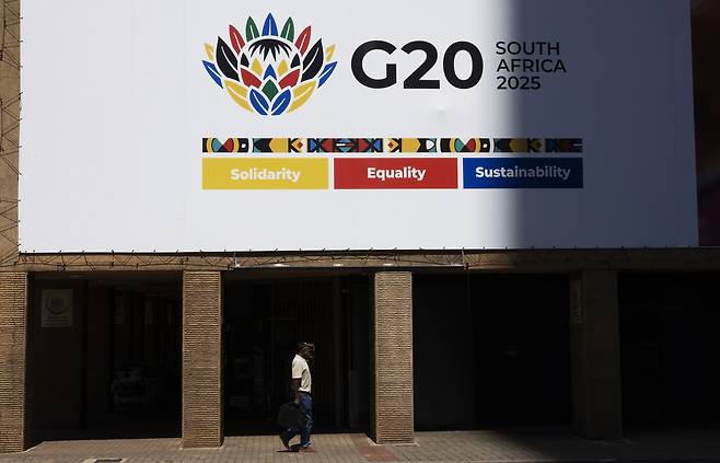 13일(현지시간) 남아프리카공화국 요하네스버그 시내의 주요20개국(G20) 정상회의를 알리는 간판 아래 보행자가 지나가고 있다. EPA연합뉴스