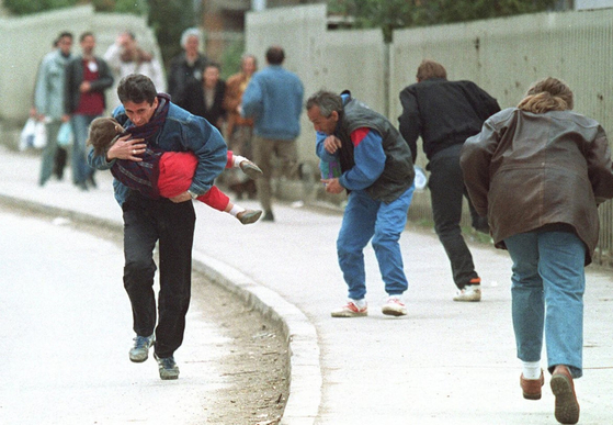 1993년 보스니아 수도 사라예보가 포위된 가운데 세르비아 저격수의 집중 공격을 받은 지역을 지나가던 사람들이 몸을 숙이고 있다. [Reuter]