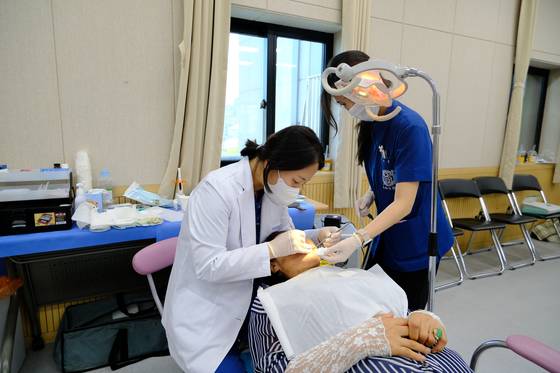 A dentist, left, operates on a patient. Photo is not related to the story. [JOONGANG ILBO]