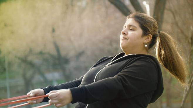 저항밴드로 운동하고 있는 비만 여성. 위고비 등 비만치료제의 핵심 성분인 GLP-1(글루카곤 유사 펩타이드-1) 호르몬을 우리 스스로 더 많이 만들어 살을 뺄 수는 없을까? 노력하면 GLP-1를 만들 수 있다. 유청 단백질과 카제인 등 성분 섭취, 운동과 장내 미생물군 관리 등 생활습관 개선 등으로 GLP-1 분비를 촉진할 수 있다. 사진=게티이미지뱅크