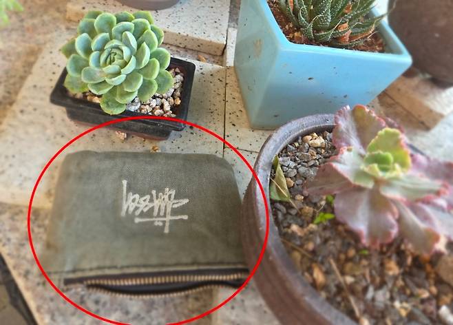 잃어버린 지갑이 집 앞 화분 옆에 놓인 모습