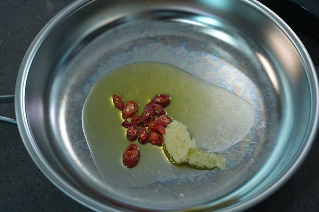 팬에 기름을 두르고 다진 마늘과 고추를 볶아 향을 내는 모습