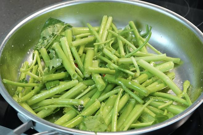 향을 낸 마늘 고추 기름에 손질한 공심채를 넣고 볶기 시작하는 과정