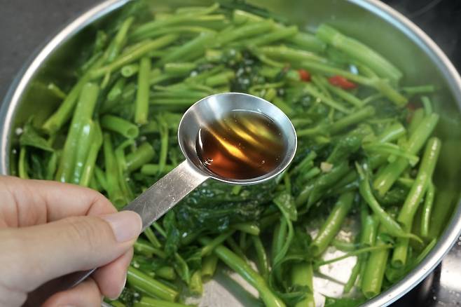 모닝글로리 감칠맛을 더해줄 피쉬소스를 계량스푼으로 넣는 모습
