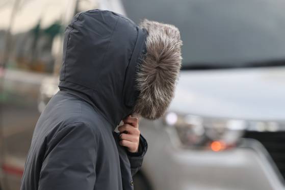 A citizen in Gwanghwamun, central Seoul, holds their coat close on the morning of Nov. 17 when temperatures suddenly dropped compared to the previous day. [YONHAP]