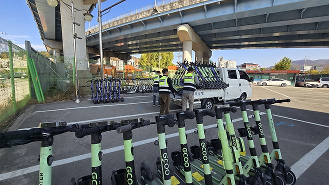 Workers unload towed electric scooters at the designated storage area for personal mobility devices inside a vehicle impound lot in Cheonan, South Chungcheong, on Nov. 11. [SHIN JIN-HO]